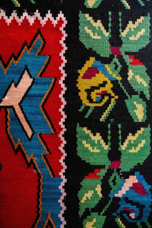 a colorful rug sitting on top of a wooden floor, a cross stitch, closeup of arms, early 2 0 th century, intarsia, 1 6 x 1 6