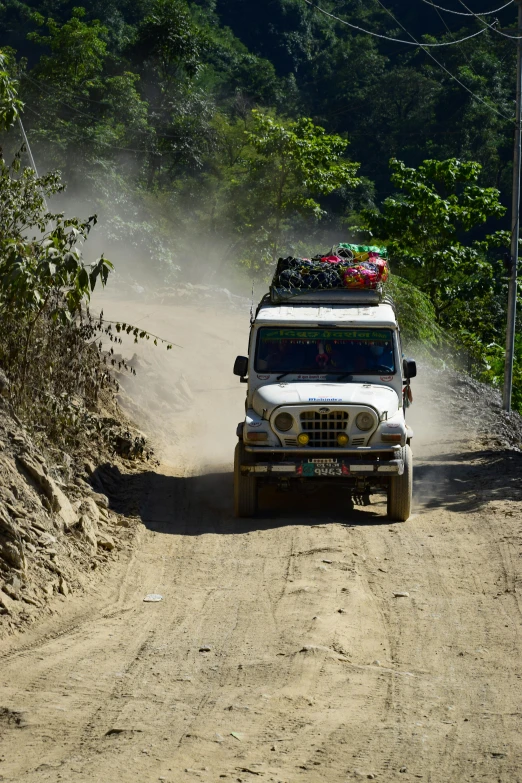 a white truck driving down a dirt road next to a forest