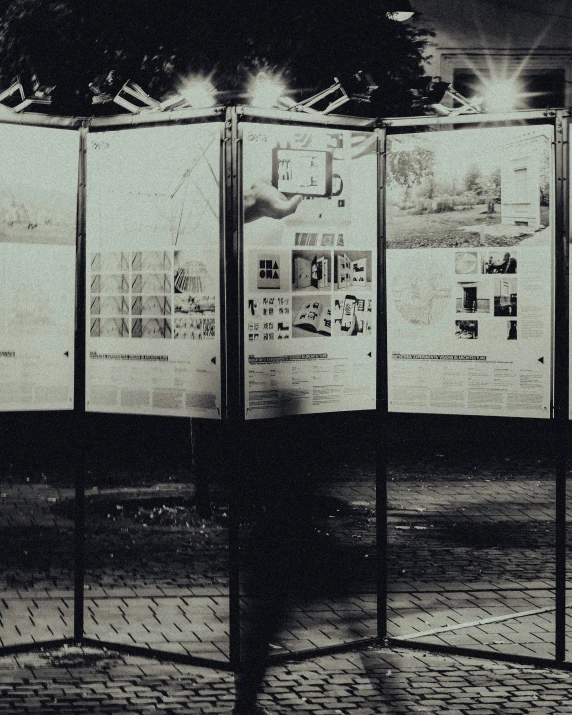 a black and white photo of a person standing in front of a display, urban planning, missing panels, holding court, a park