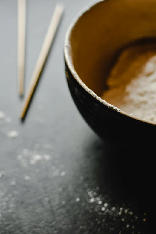 a close up of a bowl of food with chopsticks, a still life, inspired by Kanō Shōsenin, unsplash, process art, flour dust, brown, ultrafine detail ”, neck zoomed in