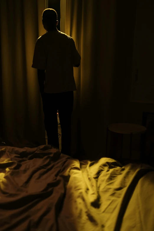 there is a man in the dark standing near a bed