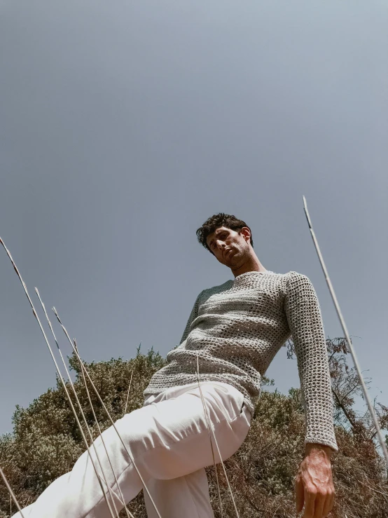 a man standing in a field of tall grass, pexels contest winner, grey sweater, standing on rocky ground, lean man with light tan skin, official store photo