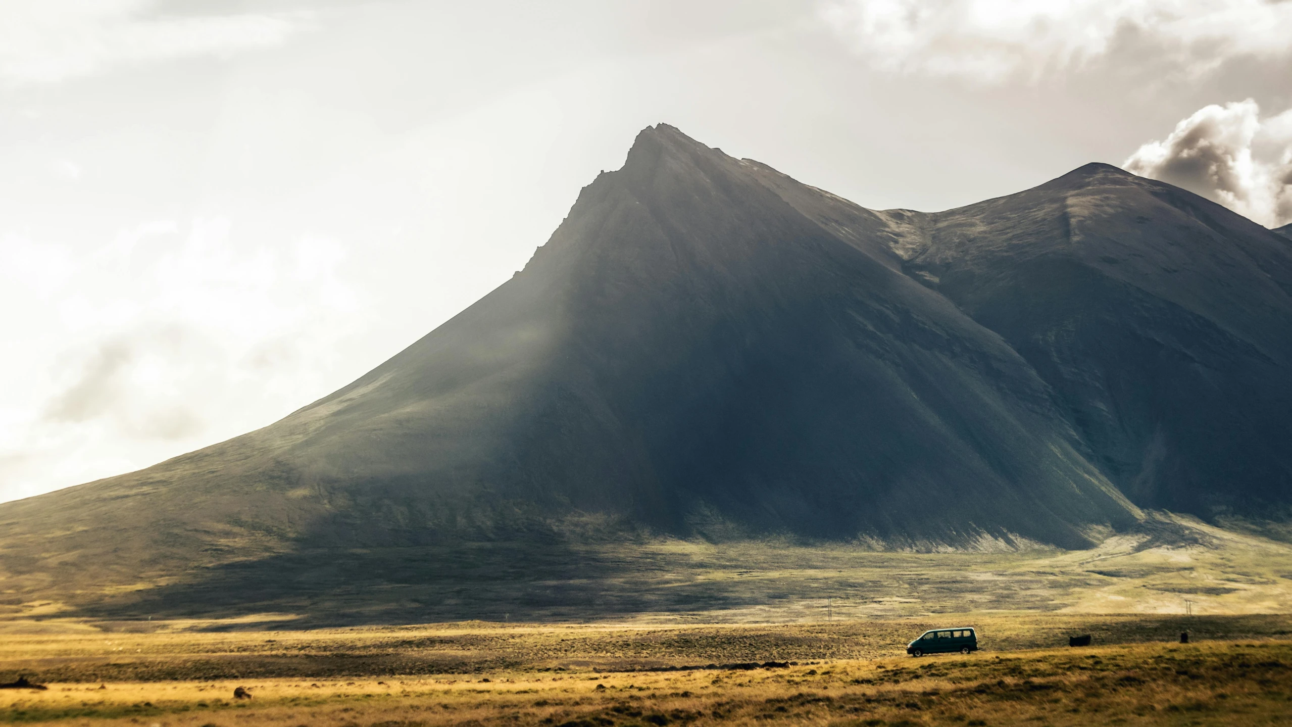 an old truck drives down the dirt road near mountains