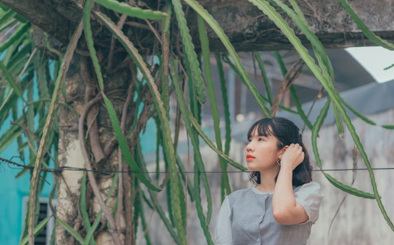 a woman standing under a tree talking on a cell phone, inspired by Ruth Jên, pexels contest winner, anime thai girl, background image, vietnamese woman, looking around a corner