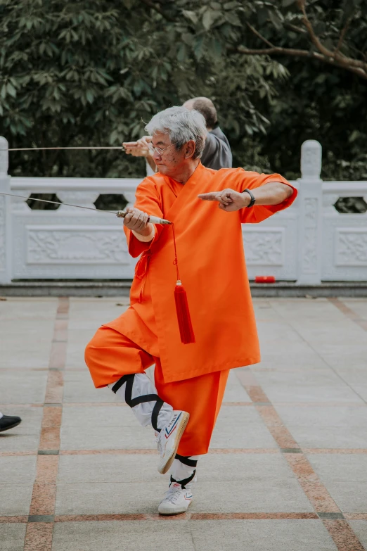 a man in an orange outfit doing a taido, inspired by Ma Quan, happening, an elderly, balance, wearing a tracksuit, avatar image