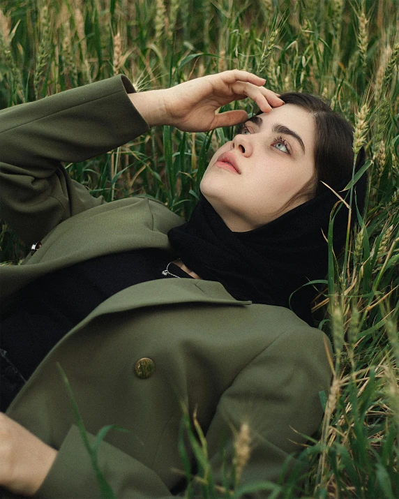 a woman lying on grass is holding her head