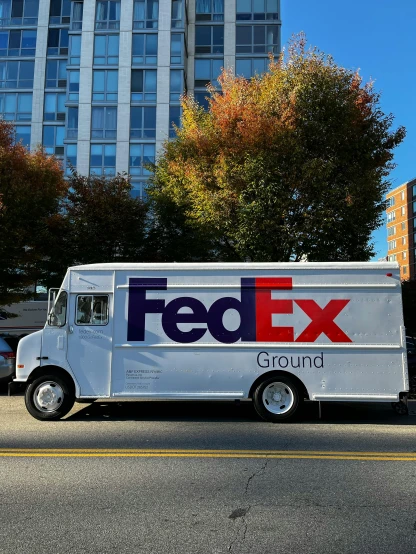 a fed ex truck parked in front of a tall building, an album cover, by Jason Felix, pexels, photorealism, 2 5 6 x 2 5 6 pixels, panoramic shot, cardboard cutout, ground broken