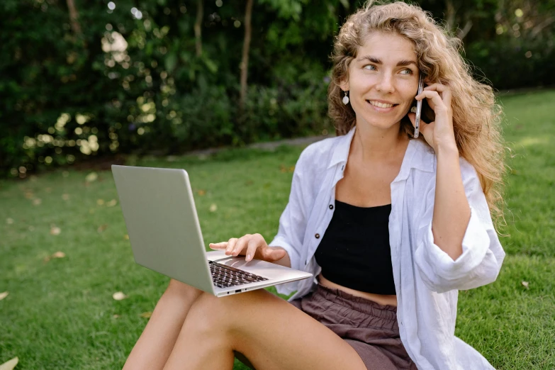 a woman sitting on the grass talking on a cell phone, trending on pexels, happening, sitting at a computer, slightly tanned, woman posing, very consistent