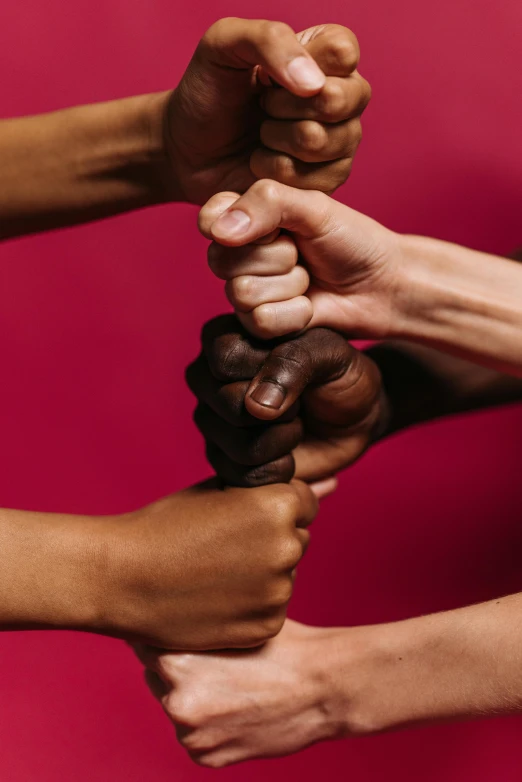 a group of people holding their hands together, by Arabella Rankin, on a red background, fist training, black man, high quality photo