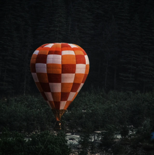 a red and white hot air balloon flying over a forest, inspired by Christo, pexels contest winner, dark grey and orange colours, sweet night ambient, inflatable, brown