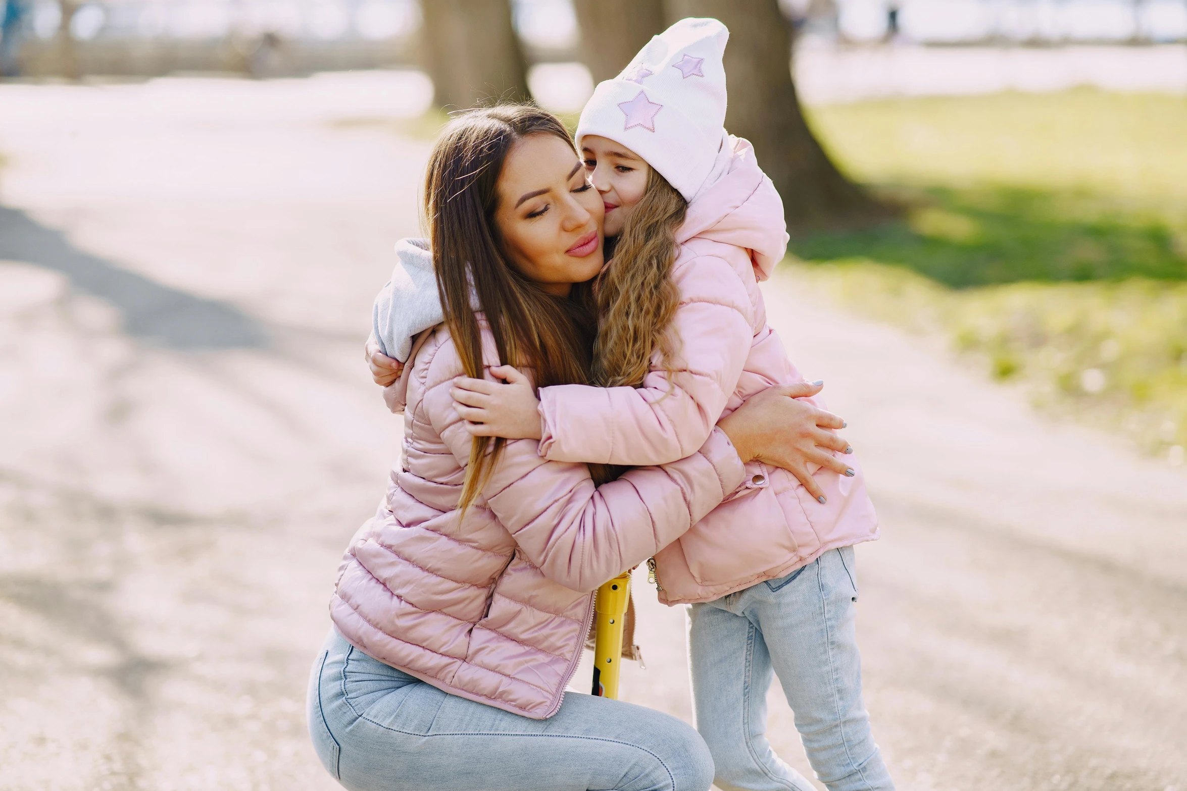 a woman is hugging a little girl on a skateboard, by Julia Pishtar, pexels, wearing a pastel pink hoodie, model wears a puffer jacket, 15081959 21121991 01012000 4k, your mom