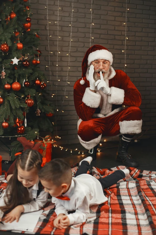 a boy reading to santa clause while sitting on the floor