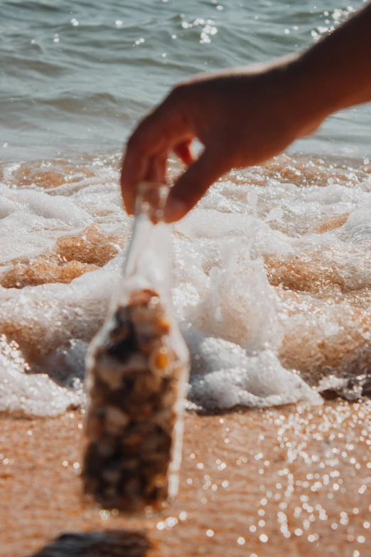 a person standing on top of a beach next to the ocean, droplets flow down the bottle, sand swirling, close up of single sugar crystal, sail