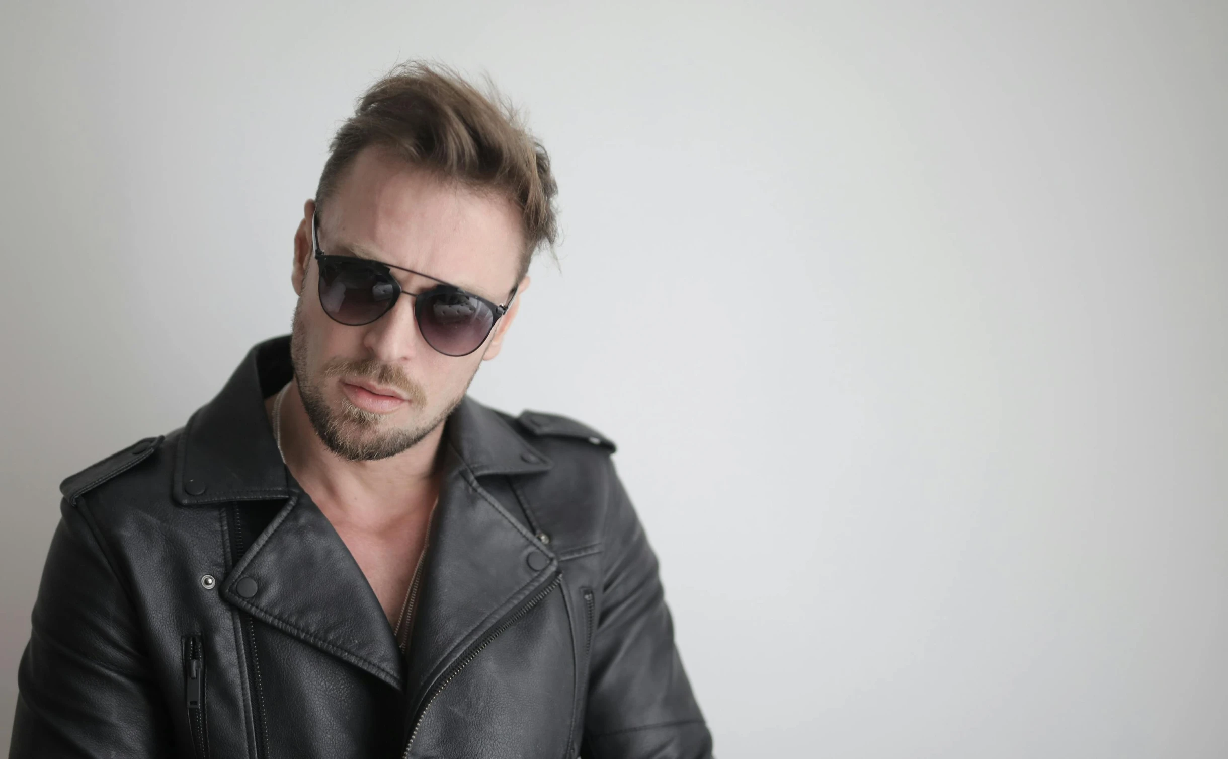 a man in a leather jacket and sunglasses posing for the camera