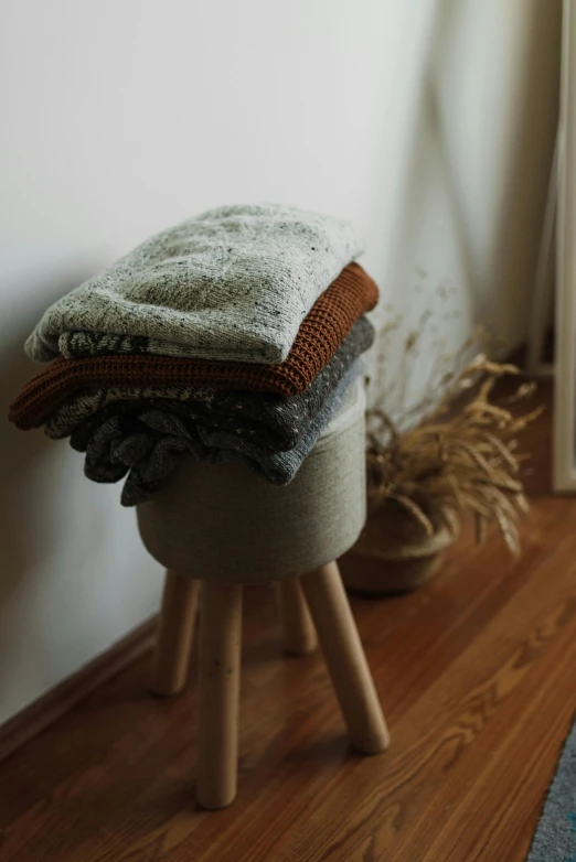 an upholstered stool with several blankets stacked on it