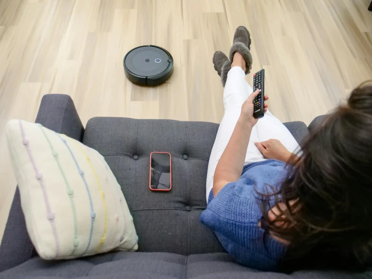 a woman laying on a couch with a remote control, niko oneshot riding a roomba, checking her phone, 15081959 21121991 01012000 4k, high-quality photo