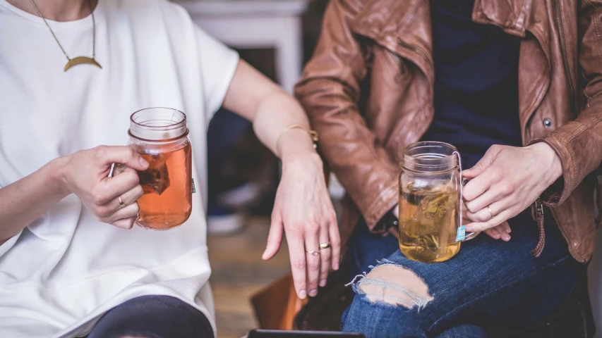 a couple of women sitting next to each other, trending on pexels, ice tea in a mason jar, hands not visible, curated collections, in the pub