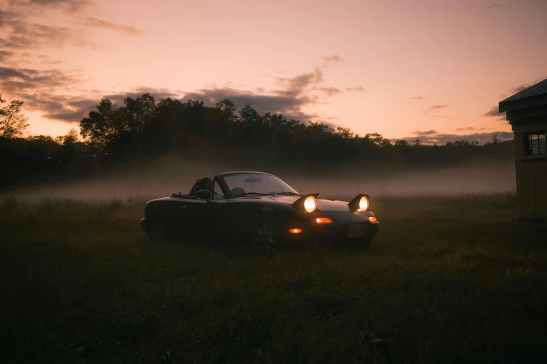 the car is parked in the field by a shed