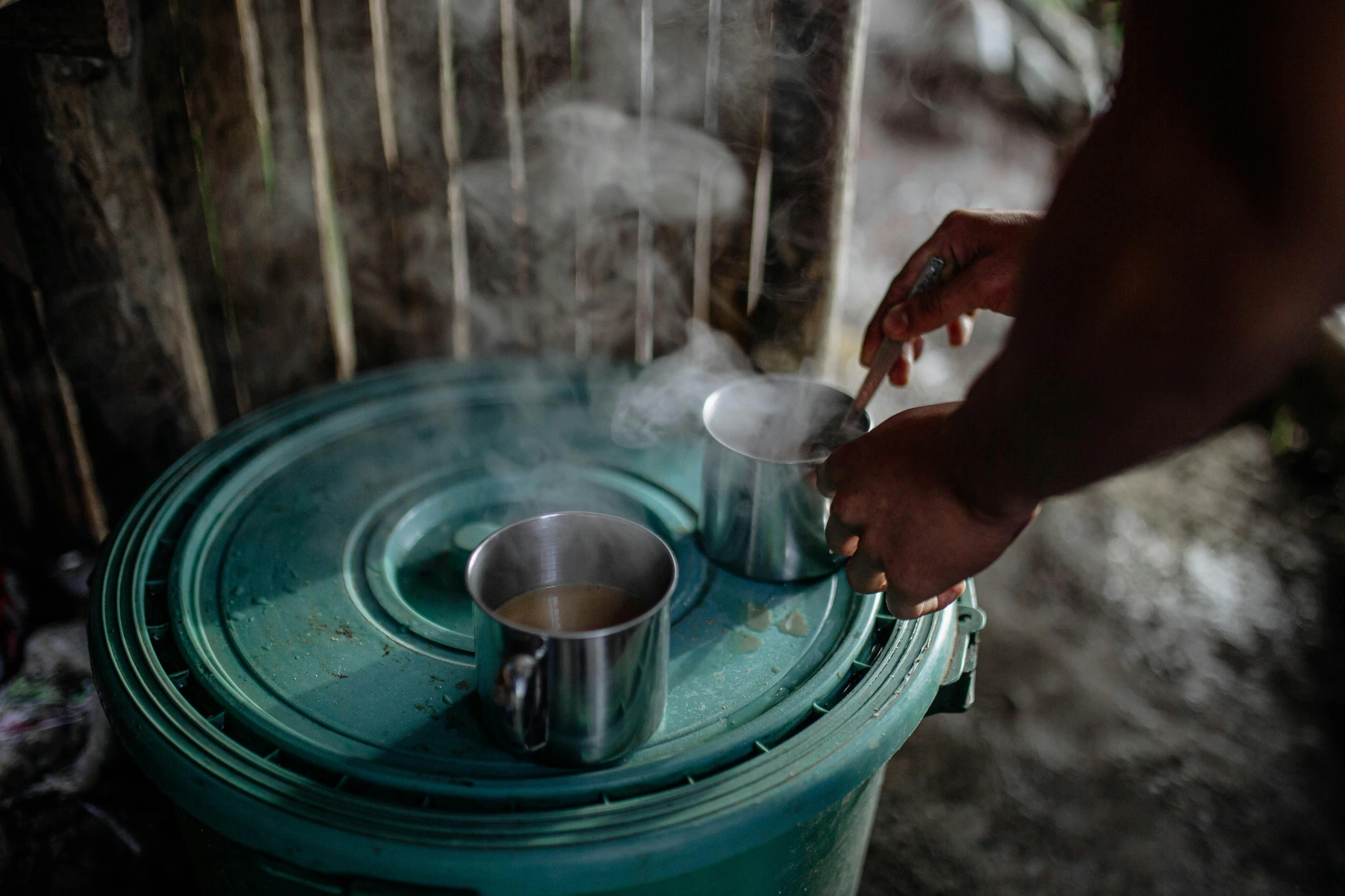 a close up of a person pouring something into a cup, by Daniel Lieske, hurufiyya, assam tea village background, real congas, two cups of coffee, photographed for reuters