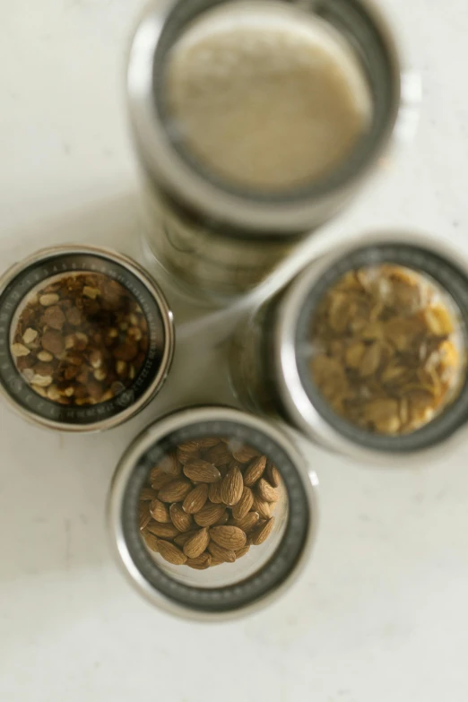 three jars filled with nuts next to a glass of milk, dau-al-set, seeds, photograph credit: ap, jamie coreth, grind