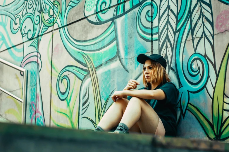 a woman is sitting against the side of a colorful wall