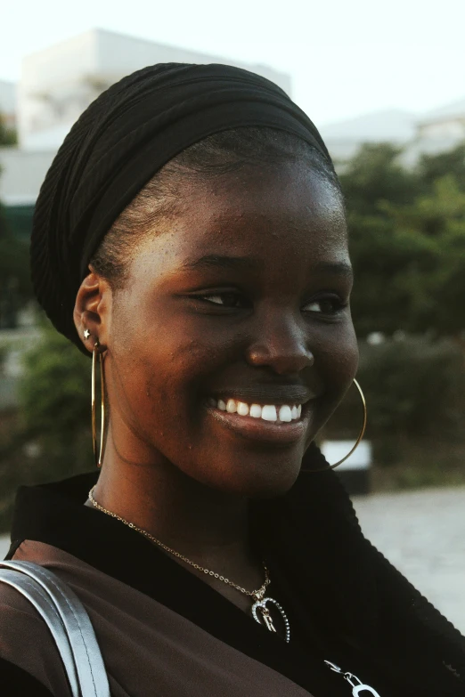 a close up of a person holding a cell phone, smiling for the camera, adut akech, wearing a headband, profile image