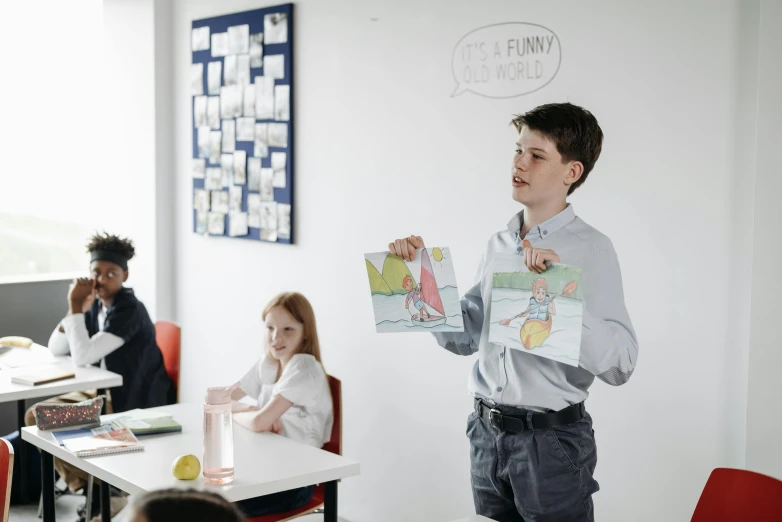 a man standing in front of a classroom full of children, a child's drawing, by Emma Andijewska, pexels contest winner, he is holding a large book, telling jokes, gif, performing