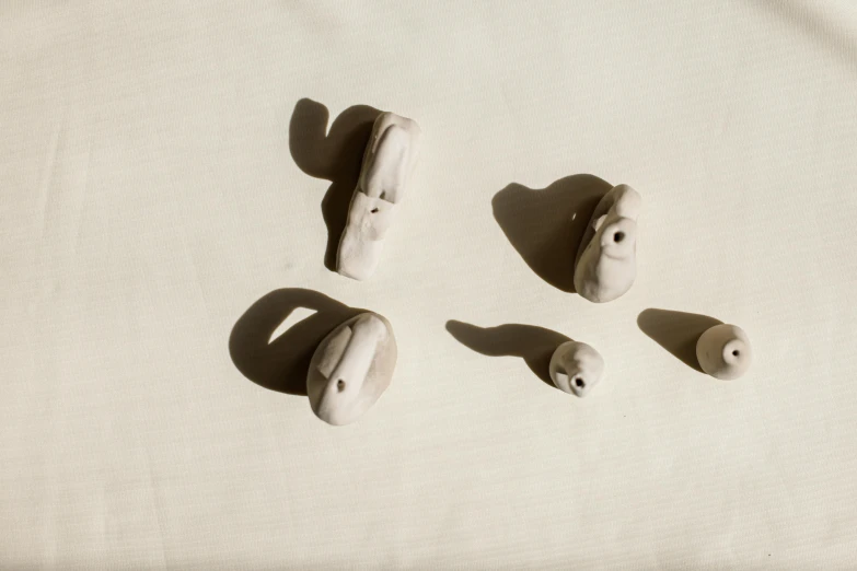 a pair of ear buds sitting on top of a table, a marble sculpture, inspired by Jean Arp, unsplash, visual art, long cast shadows, white rocks made of bone, group of seven, floating bodies