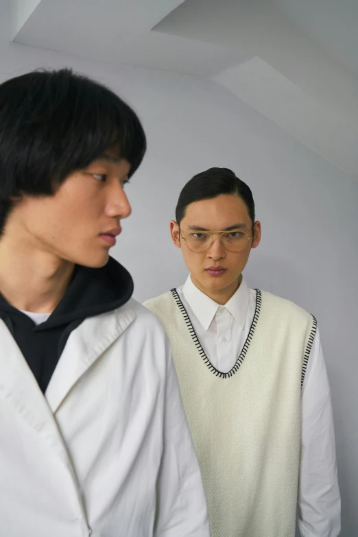 a couple of men standing next to each other, an album cover, inspired by Tadashi Nakayama, renaissance, wearing a white sweater, model is wearing techtical vest, fashion week, wearing lab coat and glasses