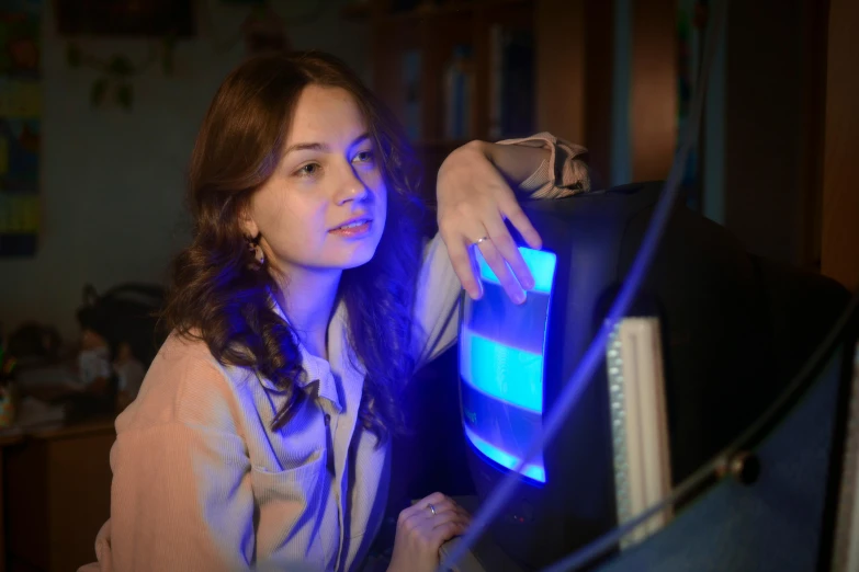 a woman sitting in front of a computer monitor, inspired by Elsa Bleda, with blue light inside, student, engineer, cinematic lut