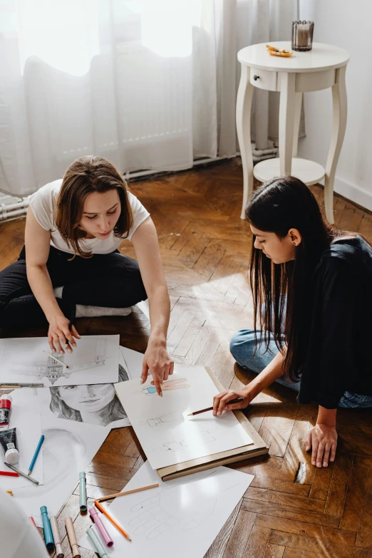 two women sitting on the floor working on a project, a drawing, by Zofia Stryjenska, pexels contest winner, behance lemanoosh, straight on portrait, promotional image, on a table