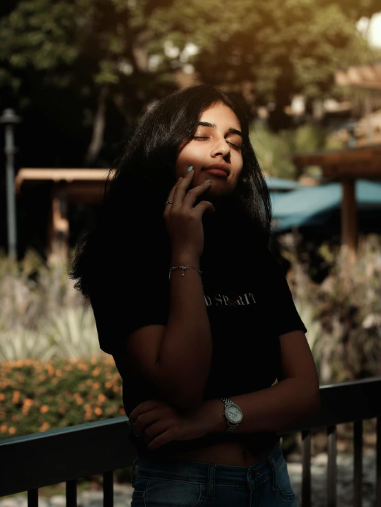 a woman standing on a balcony talking on a cell phone, a picture, inspired by Elsa Bleda, trending on pexels, realism, wearing a marijuana t - shirt, indian girl with brown skin, headshot profile picture, dark photo