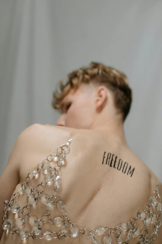 a woman with a tattoo on her back, an album cover, inspired by Claude Cahun, trending on pexels, freedom fighter, sophia lillis, at a fashion shoot, fred freeman