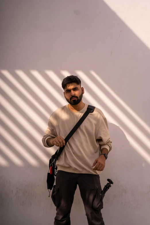 a man standing in front of a white wall, a picture, by Ismail Acar, pexels contest winner, zayn malik, with backdrop of natural light, kyza saleem, indian