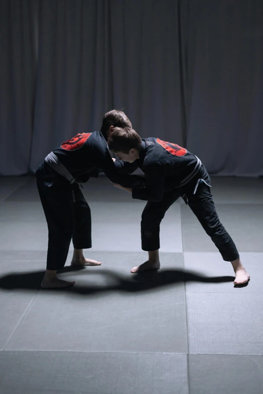a man that is standing in the middle of a floor, sparring, bend over posture, female, shodan