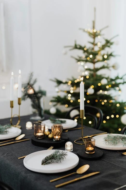 black table setting with christmas tree and gold decorations