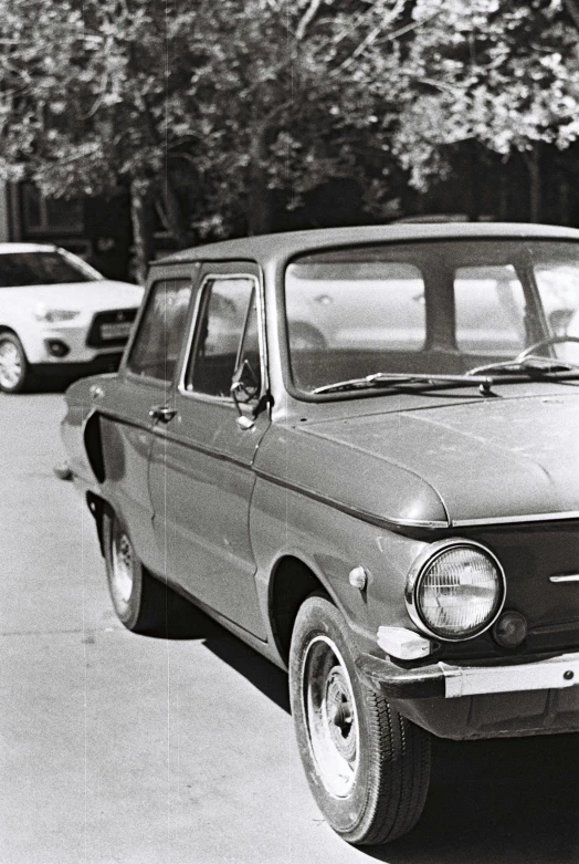 a black and white photo of a car parked on the side of the road, an album cover, lada, ffffound, tehran, 1987 photograph