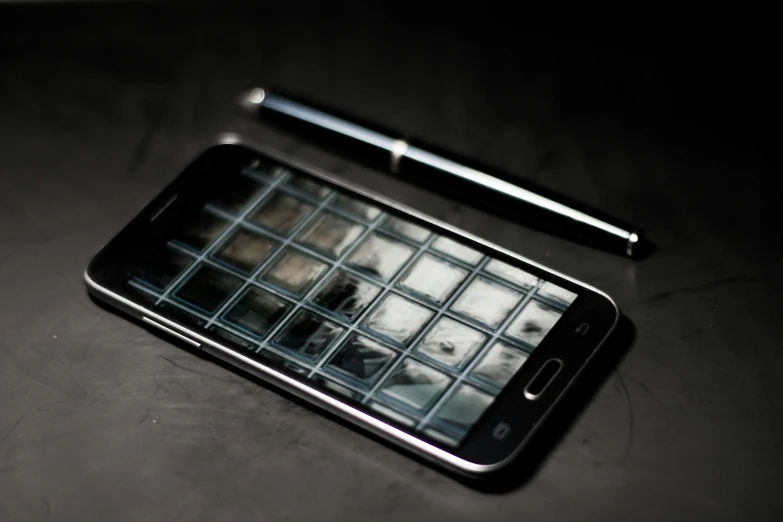 a cell phone sitting on top of a table next to a pen, a picture, by Niko Henrichon, pixabay, hyperrealism, chrome reflect, cell bars, background ( dark _ smokiness ), galaxy