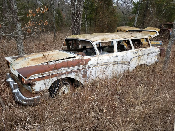 a rusted old car parked in the woods