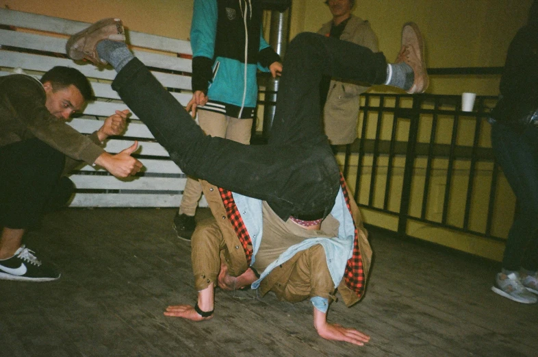 a man doing a handstand on a wooden floor, an album cover, happening, brawl, analogue photo low quality, yung lean, tournament