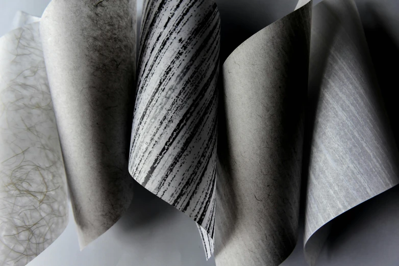 a close up of three folded napkins on a table, a charcoal drawing, inspired by Peter Zumthor, unsplash, lyrical abstraction, pristine quality wallpaper, grey and silver, various styles, parchment paper