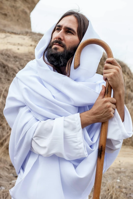 a man in a white robe holding a wooden stick, inspired by Abraham Begeyn, trending on unsplash, renaissance, camel god, ( ( theatrical ) ), jesus, wearing desert poncho