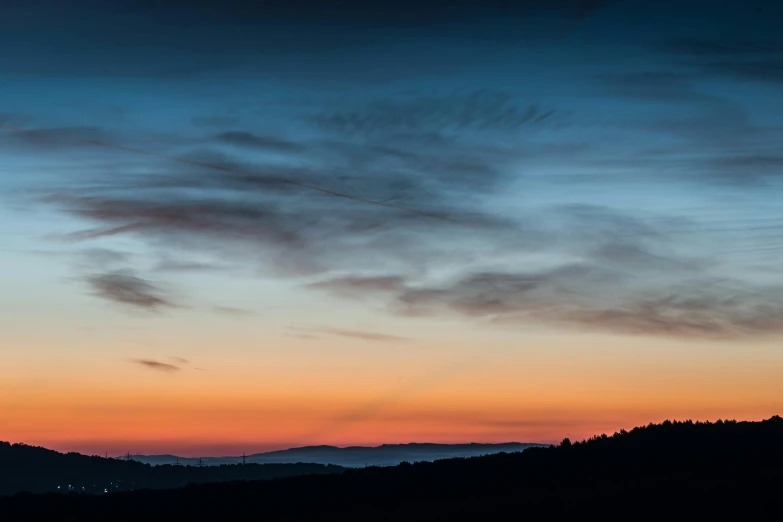 there is a plane that is flying in the sky, by Peter Churcher, pexels contest winner, romanticism, sunset panorama, muted coloures, landscape photograph, blue sunset