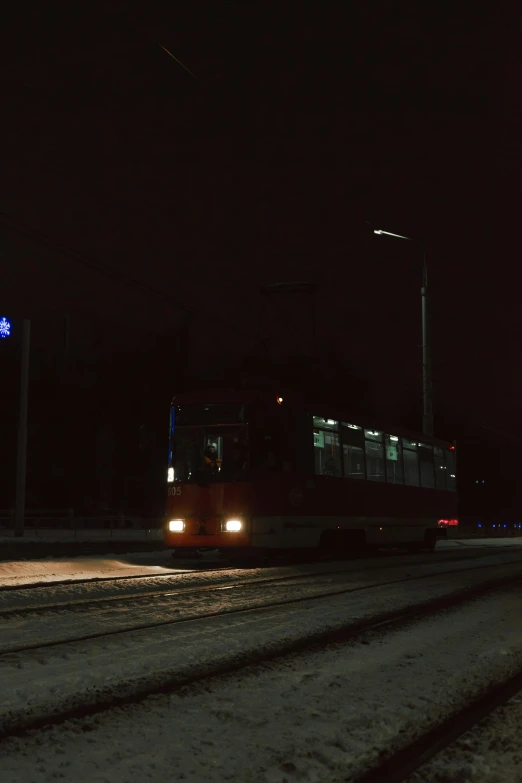 an orange and white transit bus traveling down the road at night