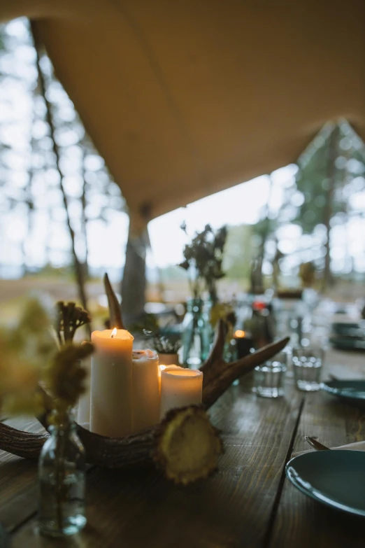 a table with candles and flowers sits beneath a tent