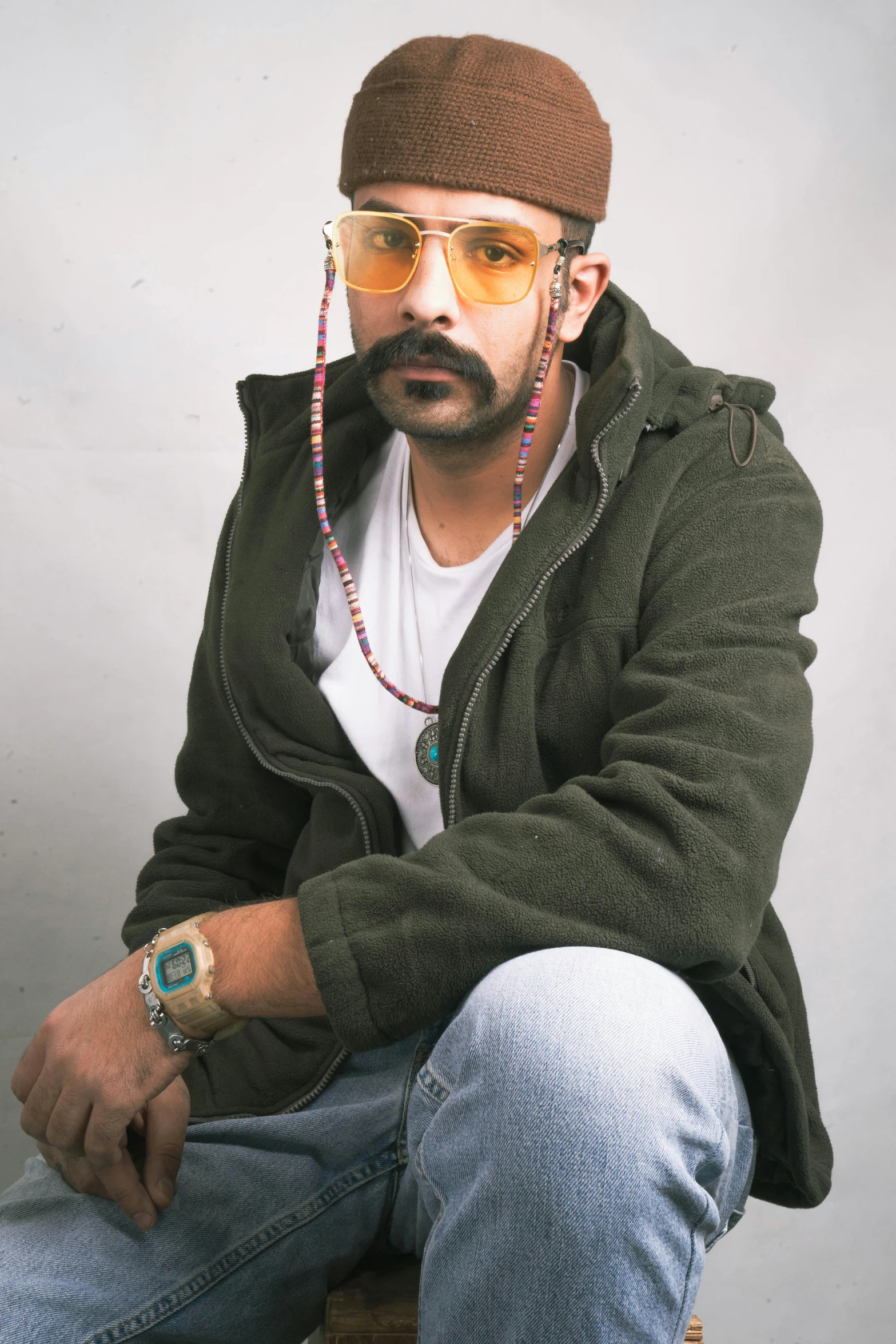 a man sitting down wearing sunglasses and a hat