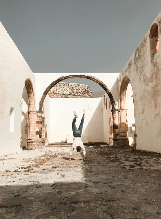 a man doing a handstand in an old building, a picture, pexels contest winner, arabesque, vacation photo, pueblo architecture, white, trending on vsco