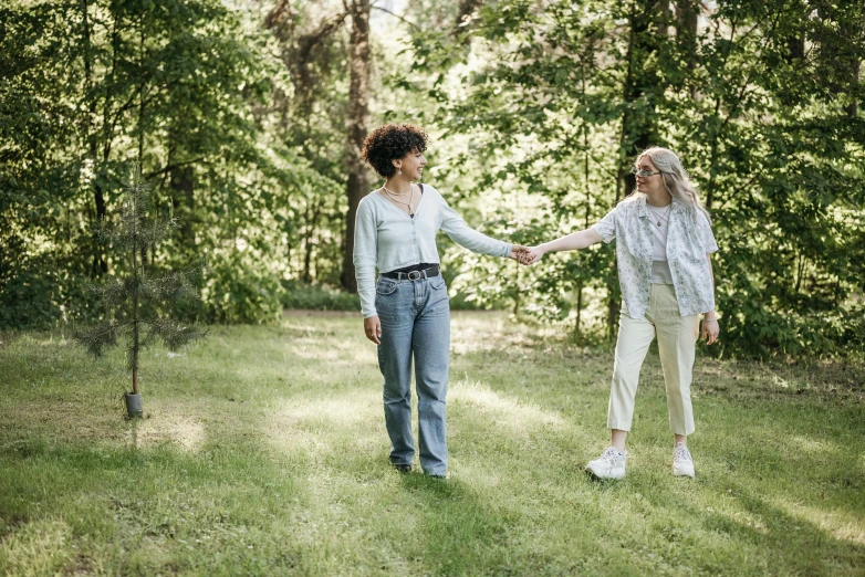 two women walking through the grass near trees