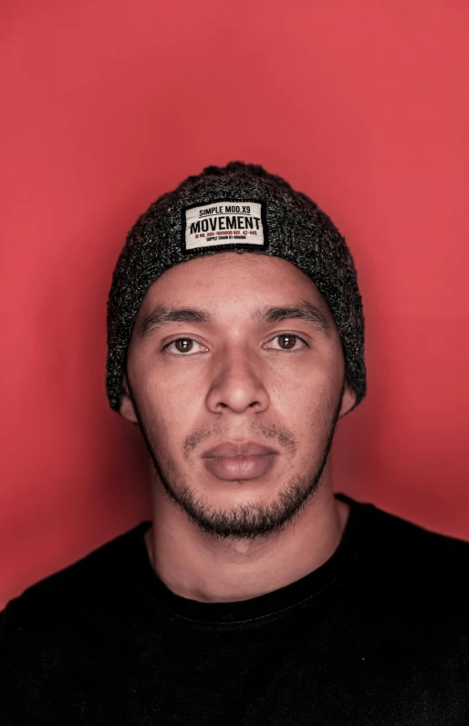 man with red background wearing a hat and black shirt