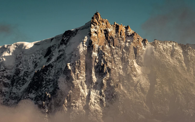 snow capped peak rising from the clouds of below